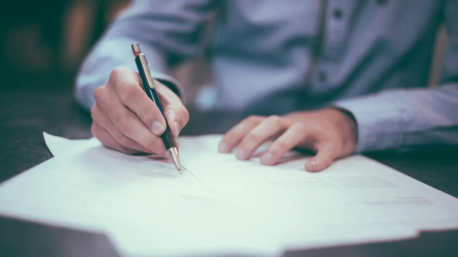 Hands signing an insurance policy document with a pen