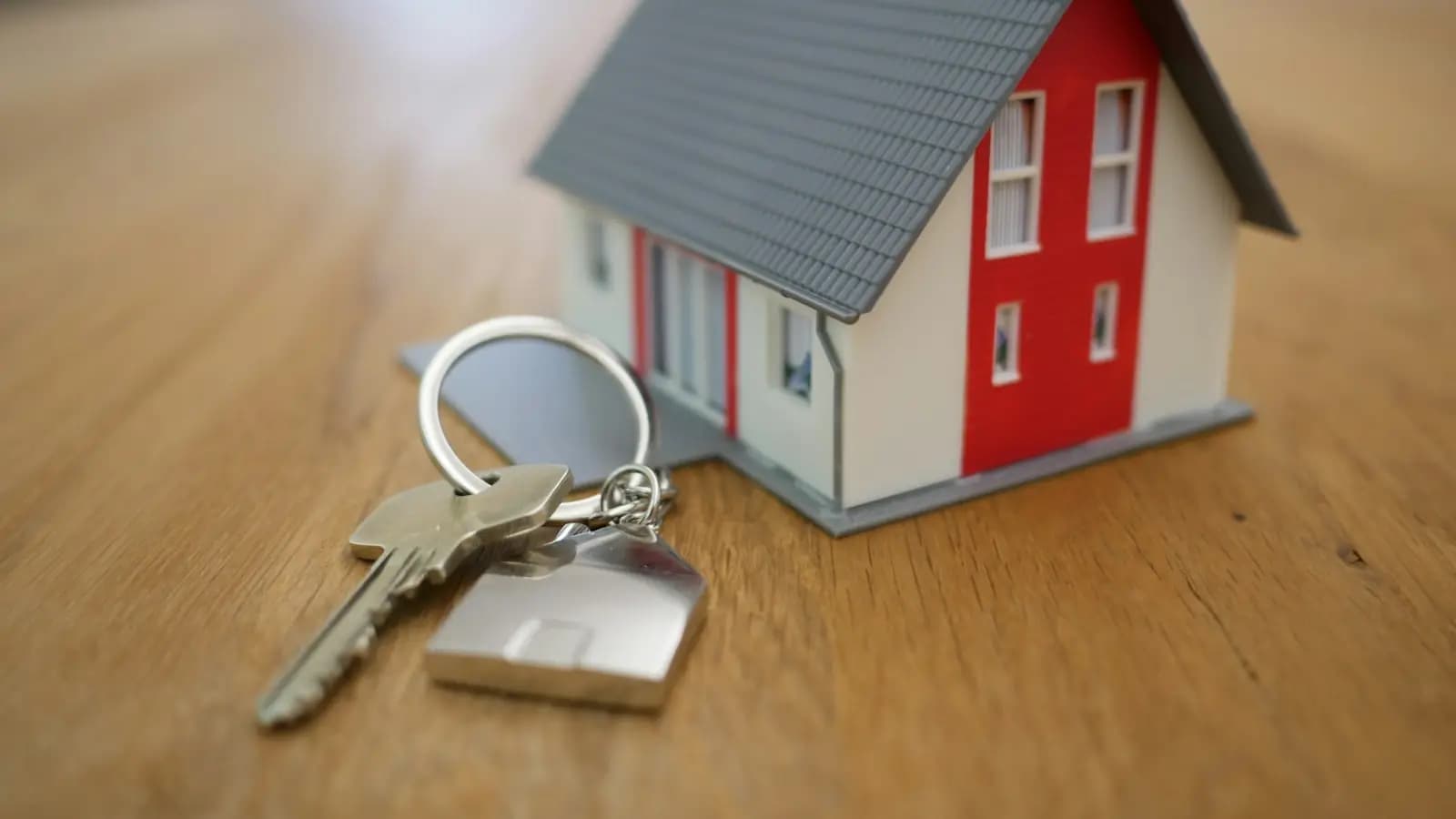 Model house with a set of keys on a wooden table